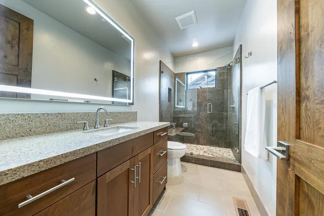 a bathroom with a sink a toilet a mirror and shower