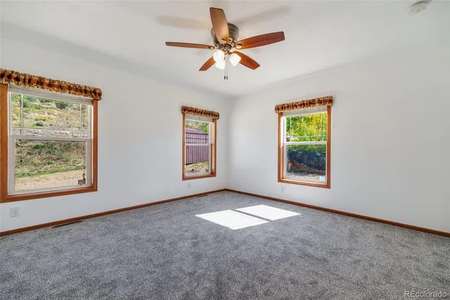 an empty room with windows and fan