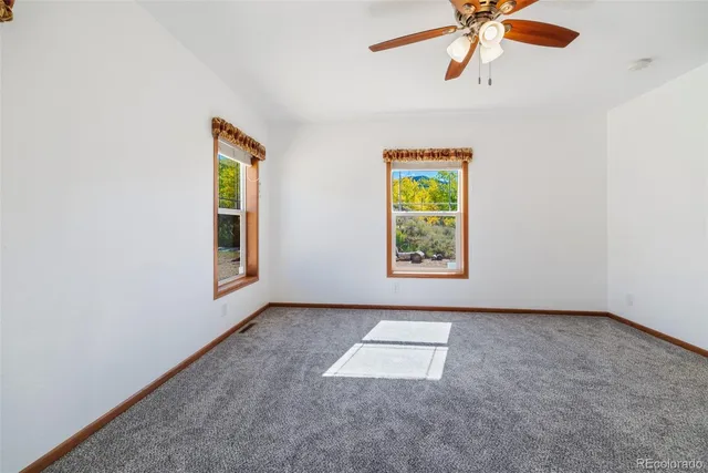 an empty room with windows and chandelier fan