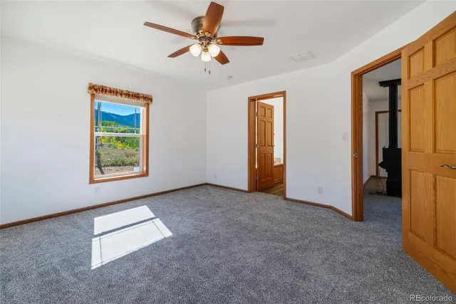 an empty room with windows and ceiling fan