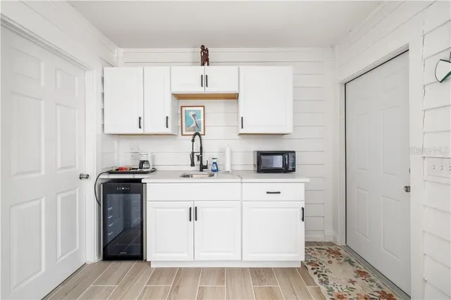 a kitchen with stainless steel appliances granite countertop a sink stove refrigerator and white cabinets with wooden floor