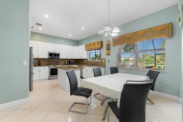 a view of kitchen with granite countertop cabinets a refrigerator and a dining table
