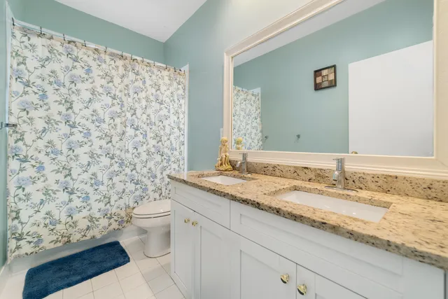a bathroom with a granite countertop sink a toilet and a mirror