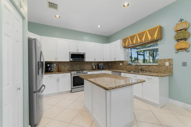a kitchen with stainless steel appliances granite countertop a sink and dishwasher a refrigerator with wooden cabinets