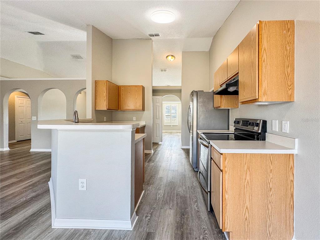 Undisclosed Address Spring Hill, FL 34609 - Photo 5 of 18 a kitchen with stainless steel appliances a refrigerator a stove a sink dishwasher and wooden cabinets with wooden floor