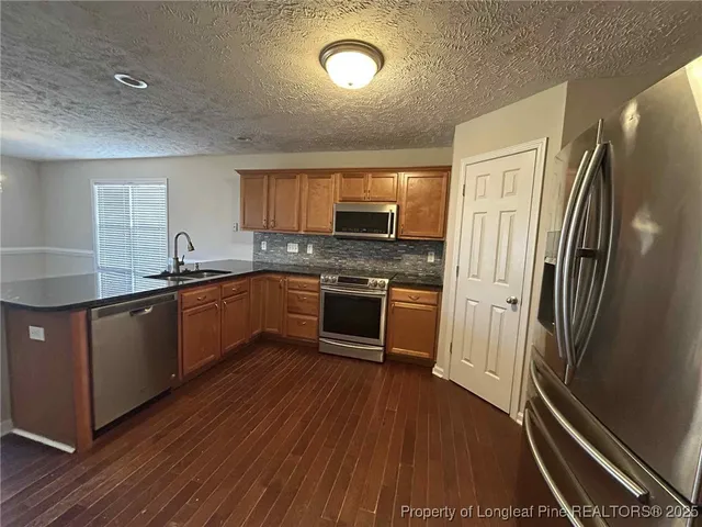 a kitchen with granite countertop a refrigerator stove and sink