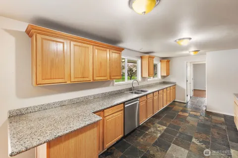 a large kitchen with granite countertop a sink and a stove top oven
