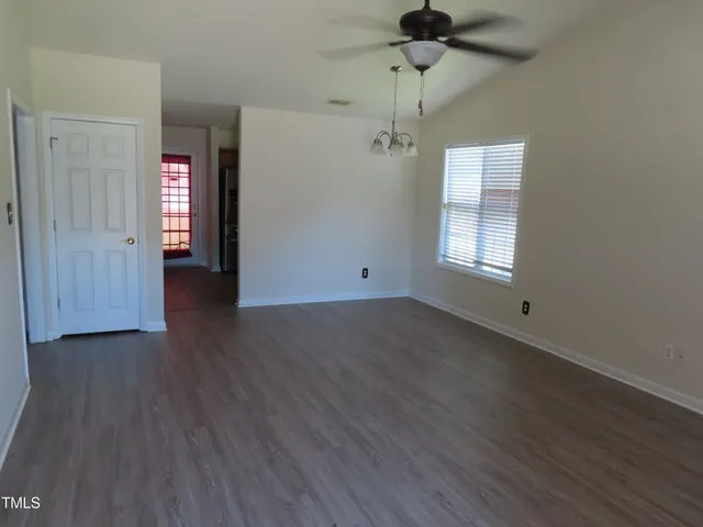 an empty room with wooden floor ceiling fan and windows