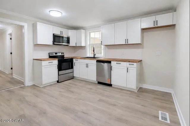 a kitchen with stainless steel appliances granite countertop a stove a sink and a microwave