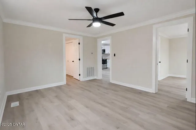 an empty room with wooden floor and ceiling fan