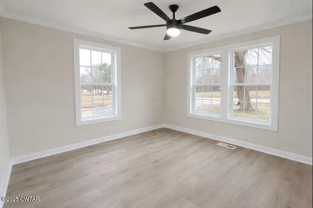 a view of an empty room with a window and wooden floor