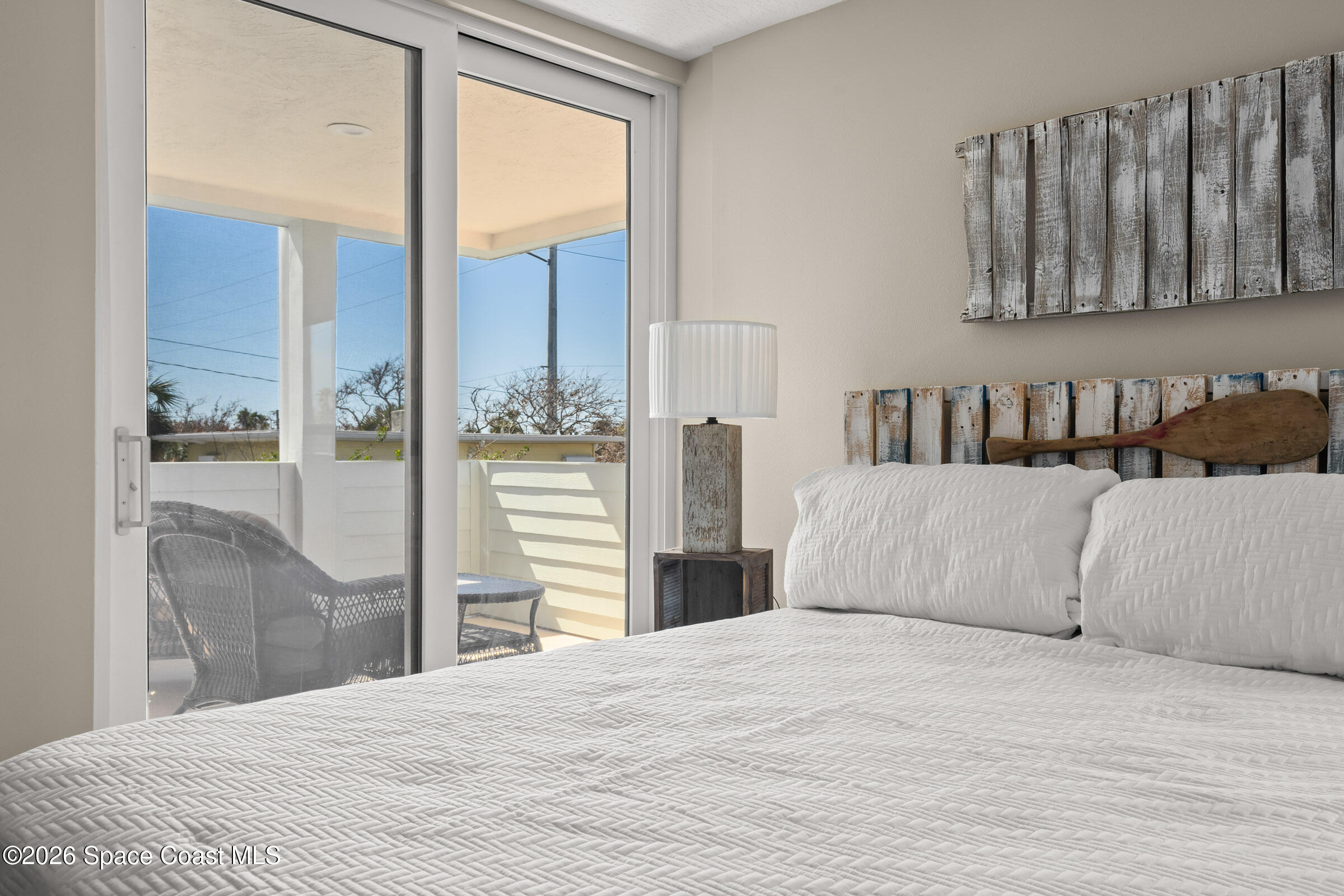 700 Wave Crest Avenue, Unit 206 Indialantic, FL 32903 - Photo 30 of 36 a bedroom with a large bed and a chandelier