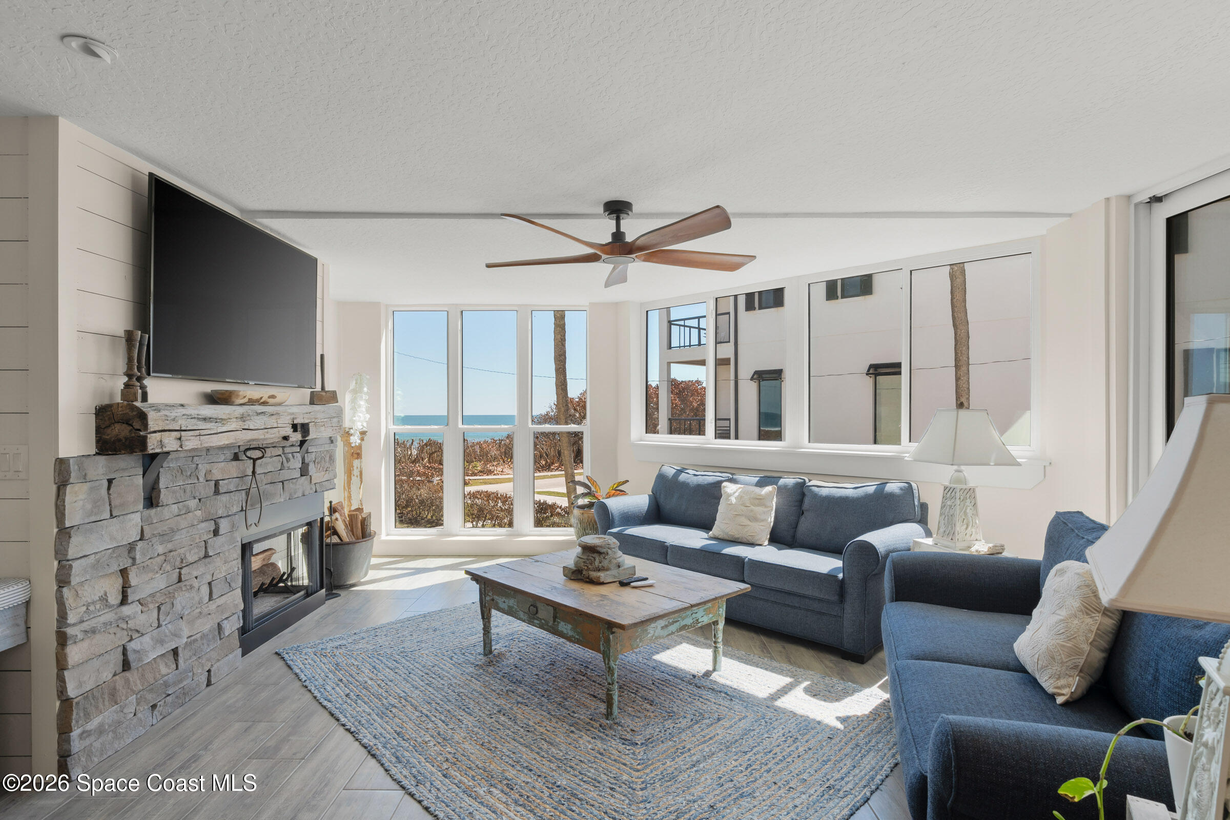 700 Wave Crest Avenue, Unit 206 Indialantic, FL 32903 - Photo 8 of 36 a living room with furniture a fireplace and a flat screen tv