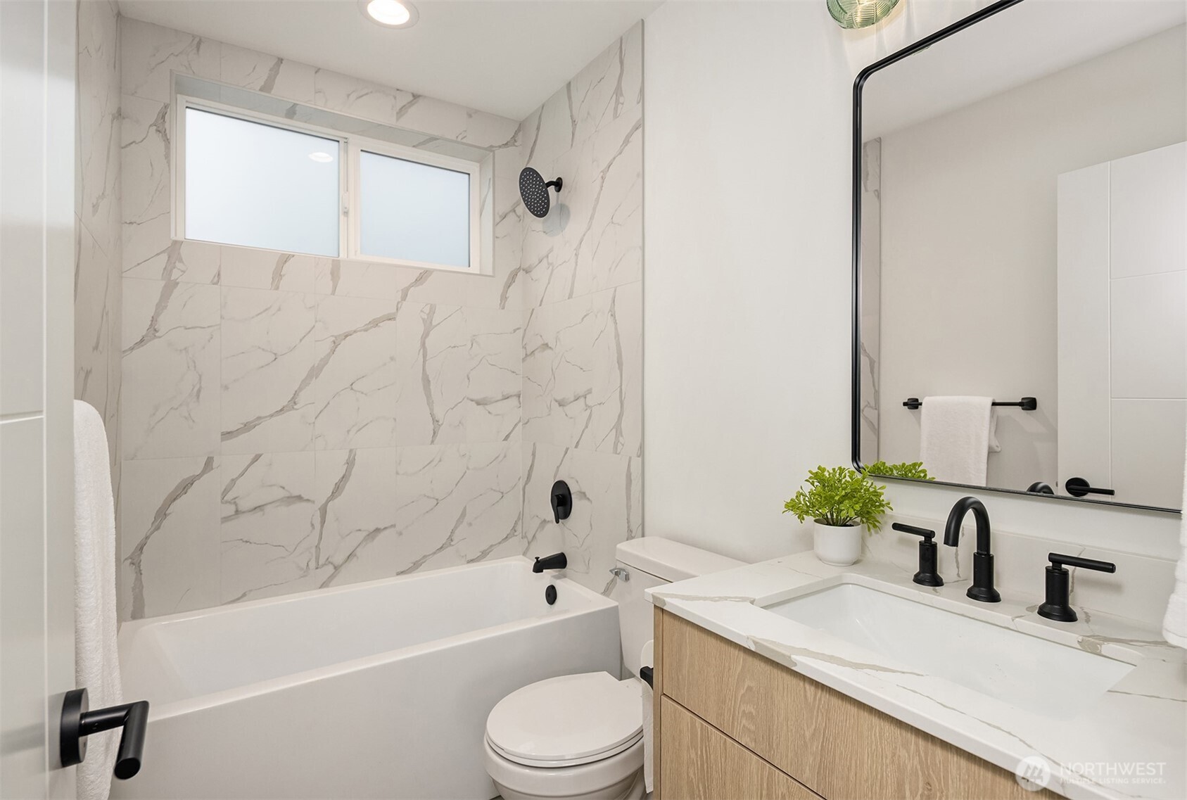 2340 North 64th Street, Unit A Seattle, WA 98103 - Photo 17 of 29 a bathroom with a granite countertop sink a toilet a mirror a bathtub and shower