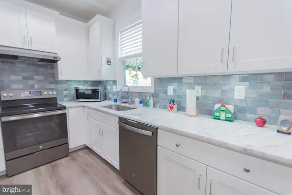 a kitchen with a refrigerator a stove a sink dishwasher and white cabinets with wooden floor