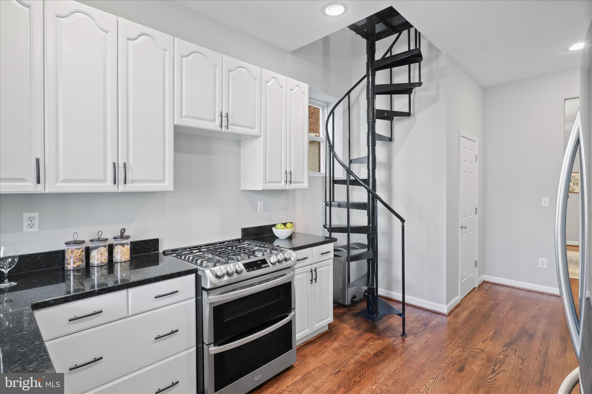 1327 Harvard Street Northwest Washington, DC 20009 - Photo 16 of 61 a kitchen with granite countertop a stove and a wooden floor
