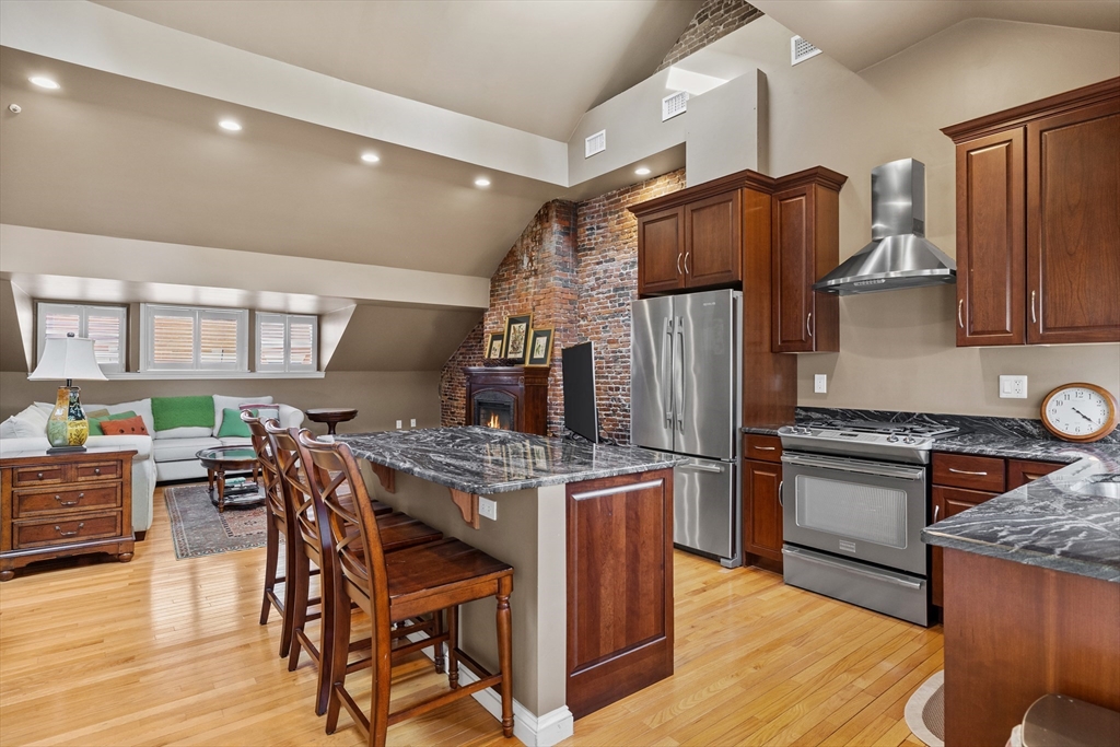 a kitchen with stainless steel appliances granite countertop a stove refrigerator and a view of living room