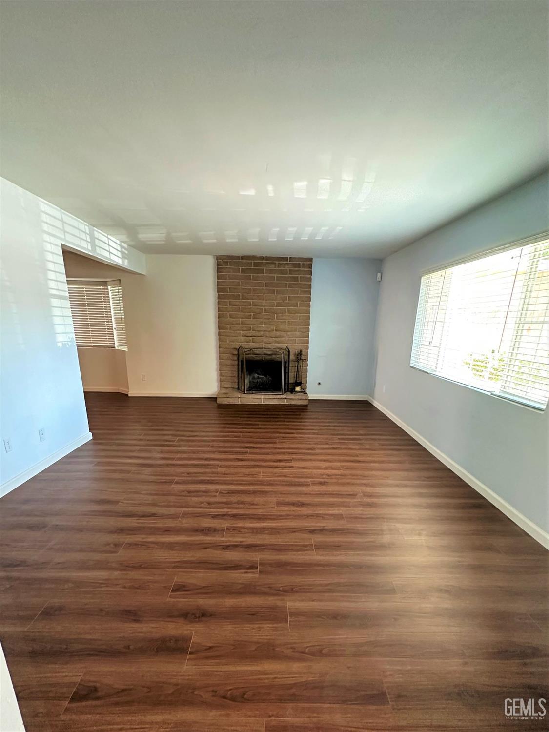 Undisclosed Address Bakersfield, CA 93306 - Photo 4 of 24 an empty room with wooden floor fireplace and windows