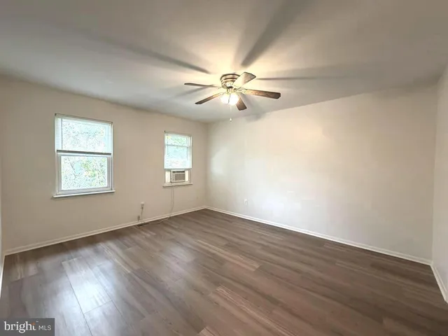 an empty room with wooden floor chandelier fan and windows