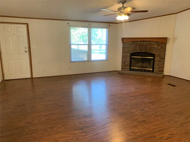 an empty room with wooden floor fireplace and windows