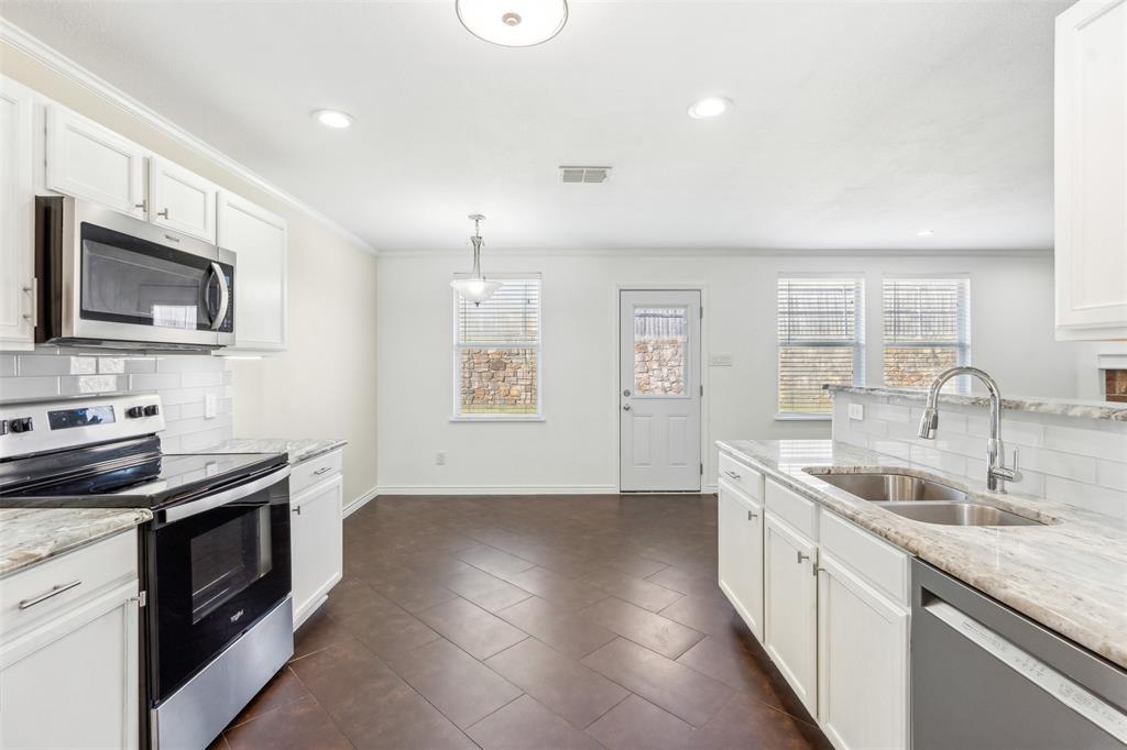 3804 McClintick Road McKinney, TX 75070 - Photo 8 of 32 a kitchen with stainless steel appliances granite countertop a sink stove and microwave