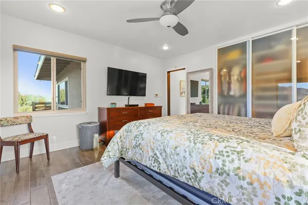 a bedroom with a bed painting on wall and two windows