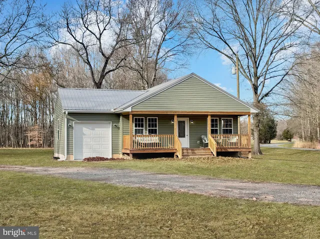 a front view of a house with a garden and trees