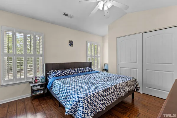 a bedroom with a large bed and wooden floor