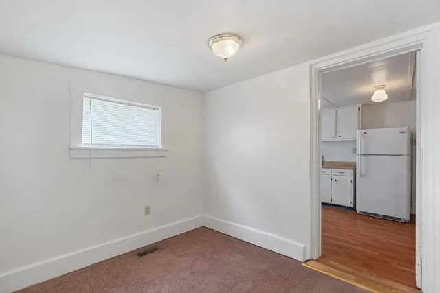 a view of empty room with wooden floor and window