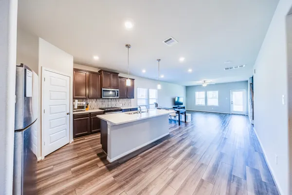 a kitchen with stainless steel appliances kitchen island granite countertop a refrigerator a stove a sink and a microwave oven with wooden floor