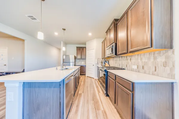 a large kitchen with stainless steel appliances kitchen island granite countertop a sink and cabinets