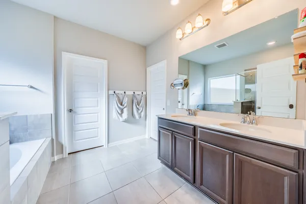 a spacious bathroom with a double vanity sink a mirror and a bathtub