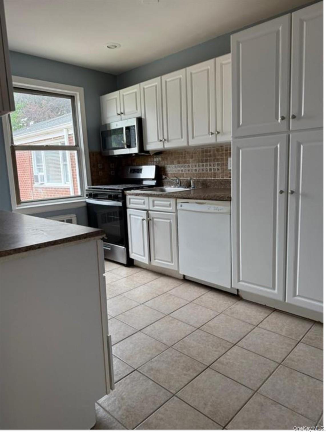 205 West Post Road, Unit 2H White Plains, NY 10606 - Photo 3 of 7 Kitchen featuring dark countertops, appliances with stainless steel finishes, white cabinetry, tasteful backsplash, and recessed lighting