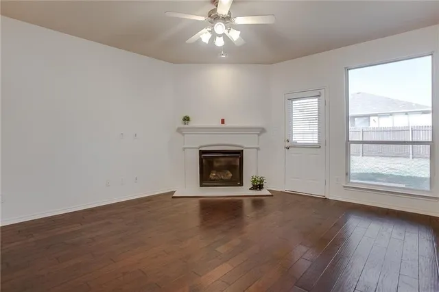 an empty room with wooden floor fireplace and windows