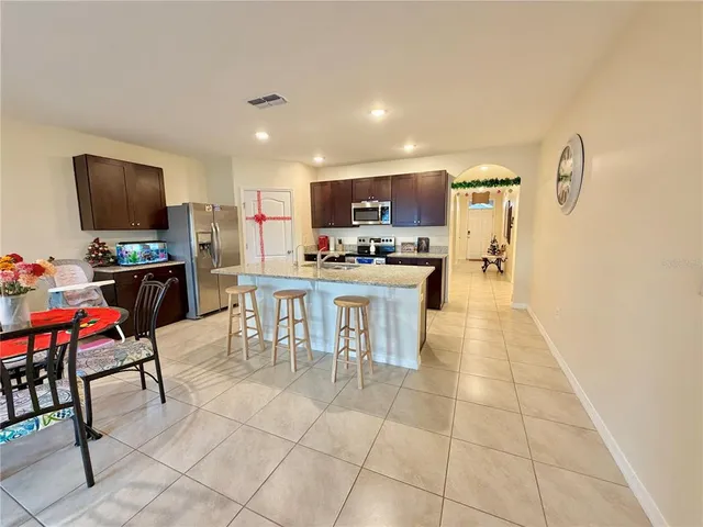 a kitchen with stainless steel appliances a stove top oven a sink a dining table and chairs
