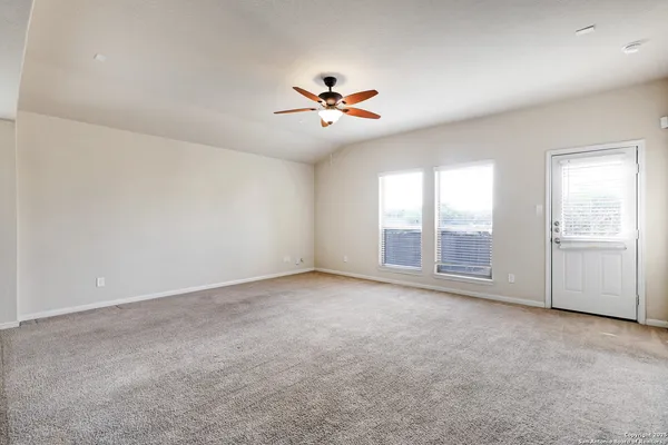 an empty room with chandelier fan and windows
