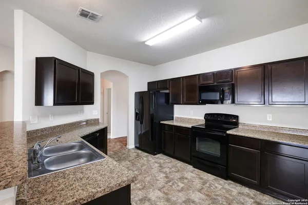 a kitchen with stainless steel appliances kitchen island granite countertop a refrigerator stove and sink