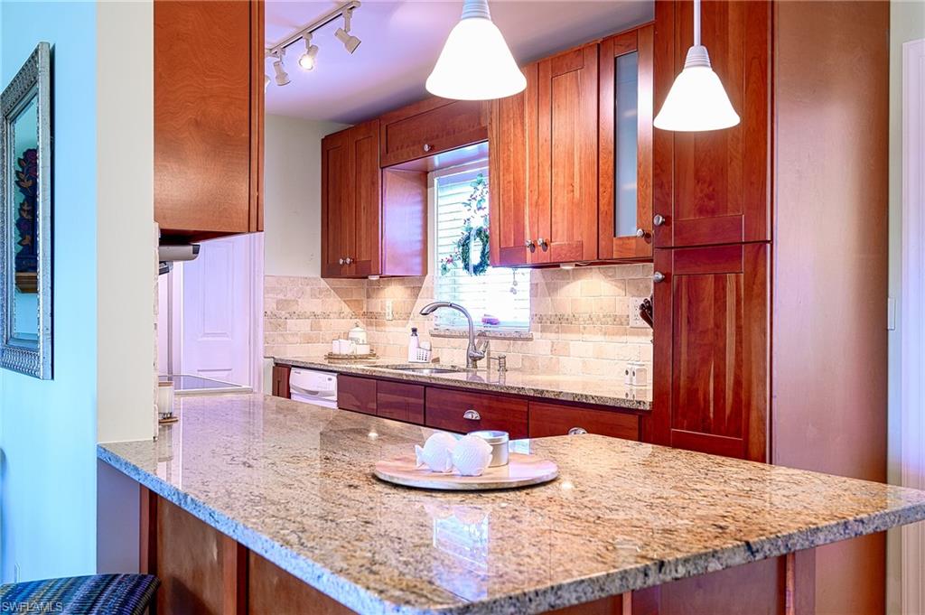 1247 Royal Palm Drive Naples, FL 34103 - Photo 16 of 28 a kitchen with kitchen island granite countertop a sink and a wooden cabinets