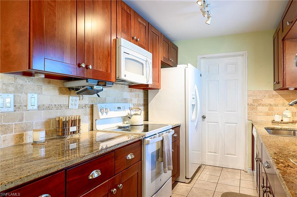 1247 Royal Palm Drive Naples, FL 34103 - Photo 18 of 28 a kitchen with stainless steel appliances granite countertop a refrigerator and a stove top oven