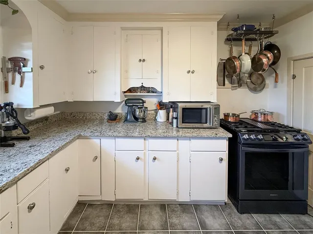 a kitchen with granite countertop a sink stove and cabinets