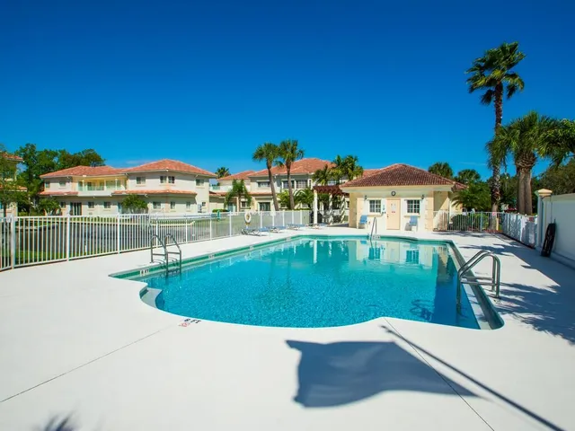 a view of a swimming pool with a lawn chairs under an umbrella