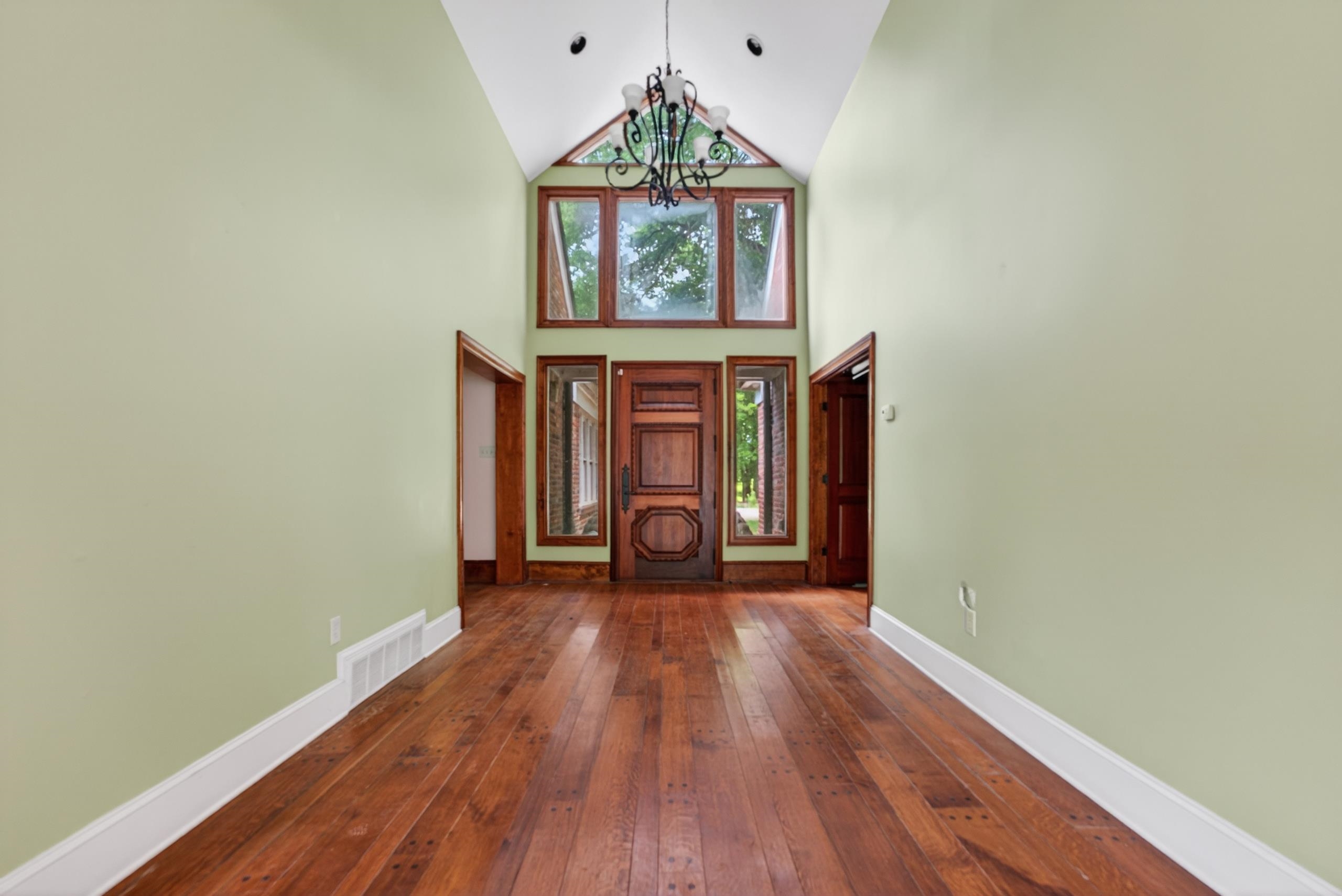 530 West Raines Road Memphis, TN 38109 - Photo 16 of 38 Grand entryway featuring high vaulted ceilings, large wood-framed windows, a decorative chandelier, and rich wood-finish flooring