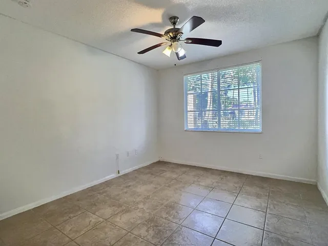 an empty room with chandelier fan and windows