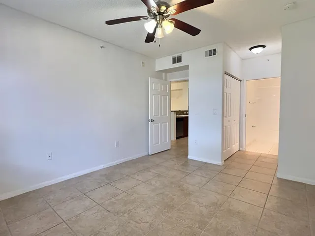 an empty room with closet and a ceiling fan