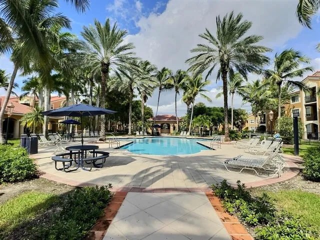 a view of a swimming pool with a table and chairs under palm trees