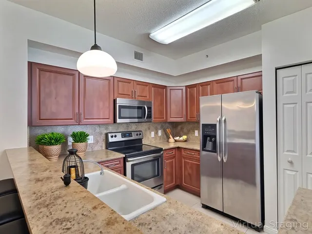 a kitchen with stainless steel appliances granite countertop a refrigerator a stove a sink dishwasher a microwave oven with a dining table and chairs