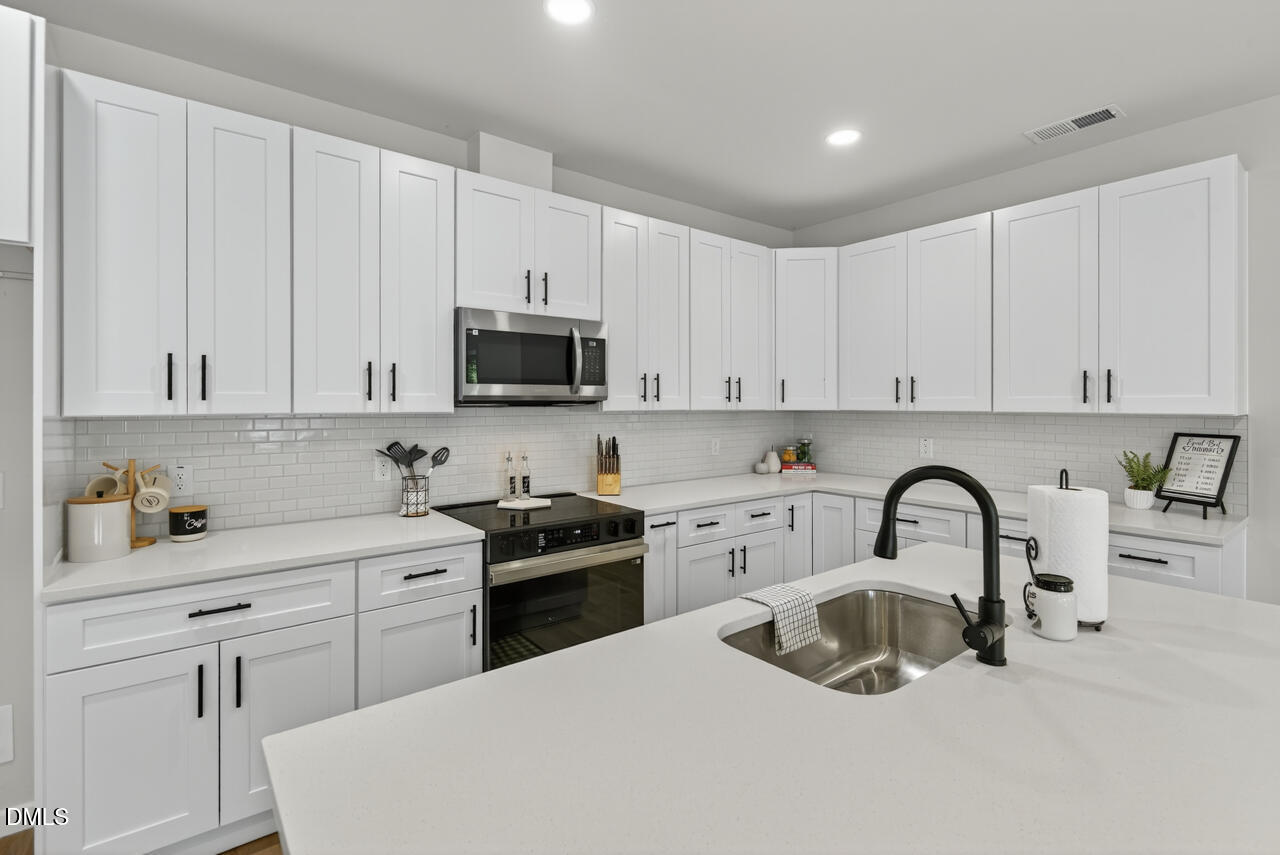 606 North Maple Street Durham, NC 27703 - Photo 20 of 51 a kitchen with white cabinets a sink and appliances