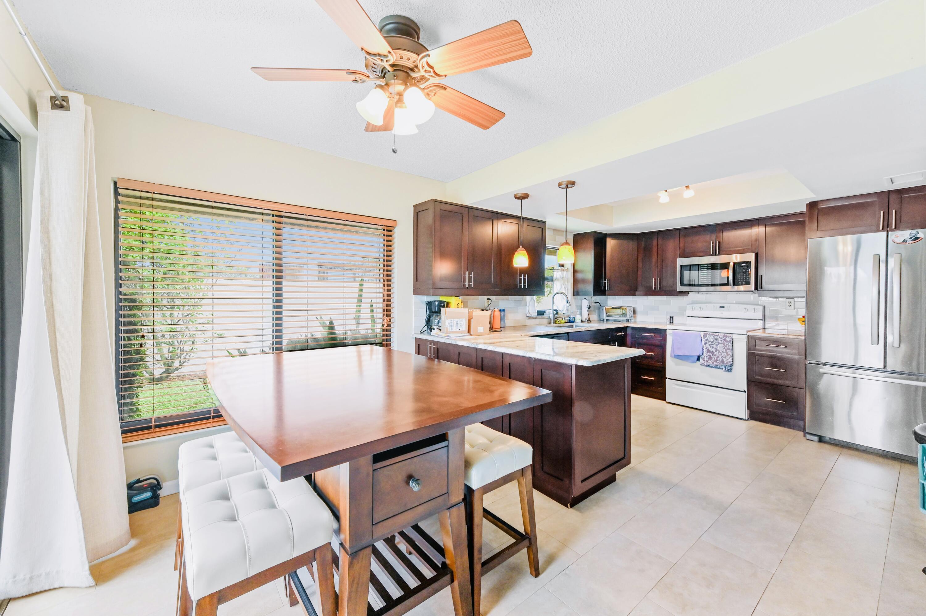2749 Southwest 5th Street Delray Beach, FL 33445 - Photo 21 of 55 a kitchen with stainless steel appliances granite countertop a sink a stove a refrigerator a microwave oven with a dining table and chairs