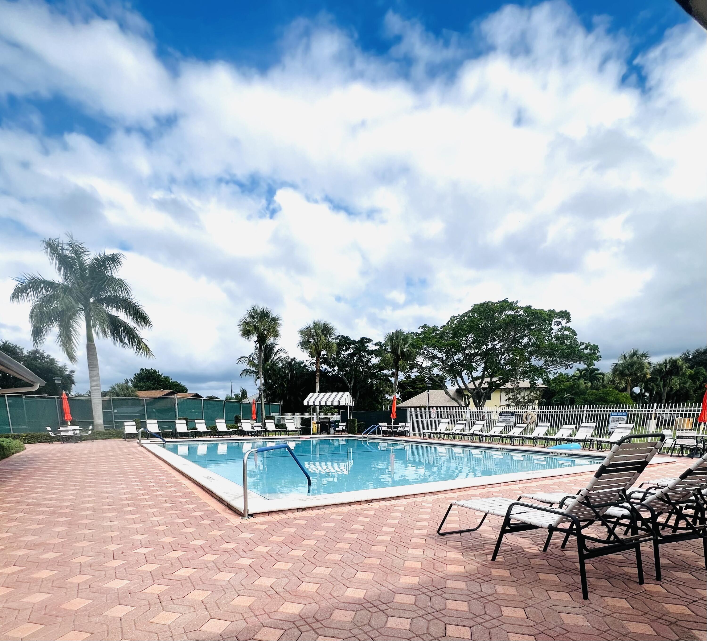 2749 Southwest 5th Street Delray Beach, FL 33445 - Photo 43 of 55 a view of swimming pool that has lawn chairs with plants and palm trees