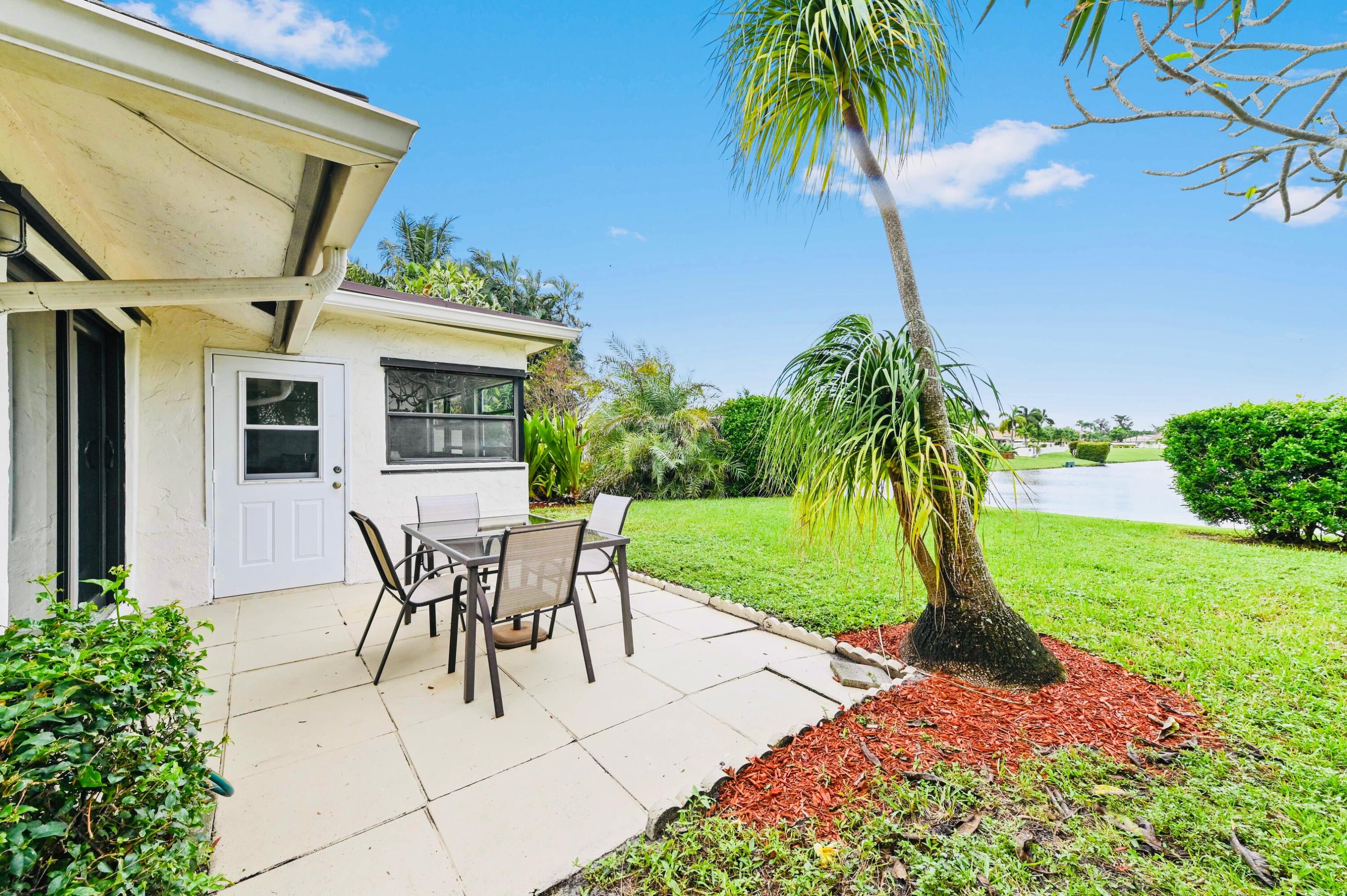 2749 Southwest 5th Street Delray Beach, FL 33445 - Photo 7 of 55 a view of a backyard with table and chairs potted plants and palm tree